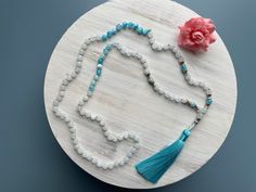 "Ukiyo 108 Bead Mala Necklace \"Ukiyo\" meaning the floating world, to live in the moment, separated from the worries of life. White Jade Blue & White Flower Jade Length- 22\" Bead Size- 6mm Thread- Muted Blue Silk Tassel- Blue Rayon Accents/Charm- Silver metal alloy  A note from the seller, K. Creative Intuition Every Mala, Every Soul Unique. Creative Intuition is the ability to realize useful creative ideas without thought. Each mala is made with this intention. If we can achieve the fluid sta Adjustable 8mm Bead Necklaces For Beach, Spiritual Round Bead Crystal Necklaces For Beach, Spiritual Crystal Necklaces With Round Beads For Beach, Adjustable Hand-strung Crystal Necklaces For Meditation, Adjustable Crystal Necklaces With 8mm Beads For Gifts, Spiritual Beaded Necklaces For Meditation With Faceted Beads, Spiritual Turquoise Crystal Necklace With Faceted Beads, Spiritual Turquoise Crystal Necklaces With Faceted Beads, Adjustable 8mm Beaded Necklace Gift