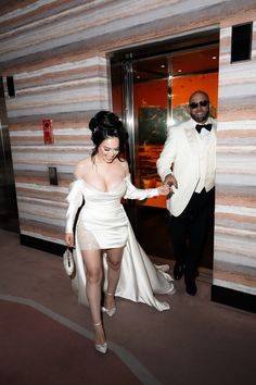 a man in a tuxedo and a woman in a white dress walking into an elevator