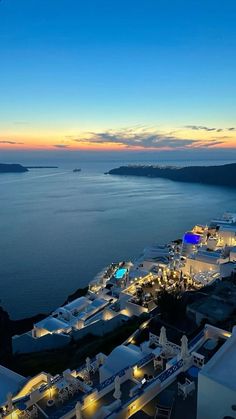 an aerial view of the ocean at dusk, with buildings lit up in blue and white