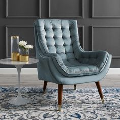 a blue chair sitting on top of a rug next to a table