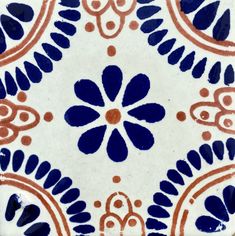 a blue and white tile with an orange flower on it's center, is shown