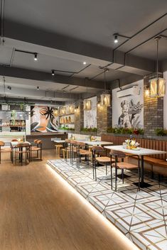 the interior of a restaurant with tables, chairs and artwork on the wall behind them