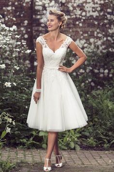 a woman standing in front of flowers wearing a white dress