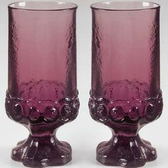 two purple glass vases sitting next to each other