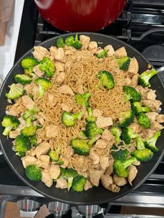 broccoli and noodles are being cooked in a wok on the stove top