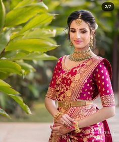 a woman in a red and gold sari posing for the camera with her hands on her hips