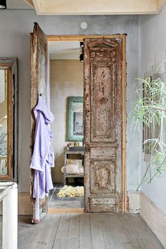 an open door leading to a bathroom with a plant in the corner and other items on the floor