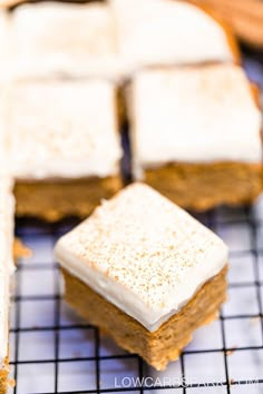 there are several square pieces of cake on the cooling rack, and one is frosted with white icing