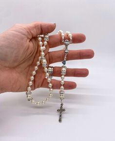 "This beautiful rosary was handcrafted with beautiful and genuine premium Austrian crystal pearls, silver-finished rhinestone rondelles, and accented with sparkly glass seed beads and sterling silver accents. The Our Father beads are framed by silver-finished rhinestone rondelles. The silvertone chalice centerpiece, imported from Italy, is 7/8\" long, and the silver tone intricately detailed crucifix is just over an inch long. Just under the centerpiece is a sterling silver heart letter bead with an initial. This is a perfect First Holy Communion gift that she can carry with her for the rest of her life.  Your rosary will arrive in an organza pouch and nestled in a ribbon-tied jewelry box, perfect for gift giving!  * This rosary allows for ONE letter. Additional letters may be purchased he Silver Beaded Rosary For First Communion, Silver Pearl Rosary With 8mm Beads, Silver Pearl Rosary For First Communion, Pearl Rosary With 8mm Beads For Wedding, Pearl Rosary Bracelet For Weddings, Elegant Adjustable Rosary With Silver Beads, Adjustable Silver Pearl Rosary, Spiritual Pearl Rosary Bracelet For Wedding, Elegant Adjustable Silver Beads Rosary