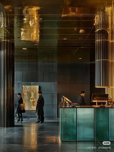 two people standing in front of a counter with gold decorations on the wall behind them