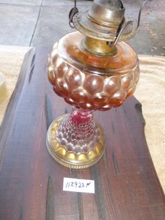 an old fashioned lamp sitting on top of a wooden table next to a glass container