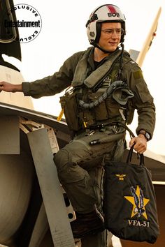 a man in uniform sitting on the wing of an airplane