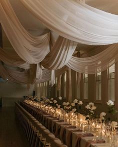 the tables are set up with candles and flowers in vases on each side, along with draping over them