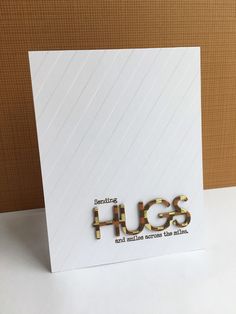 a greeting card with the words hugs and gold foil on it, sitting on a white surface