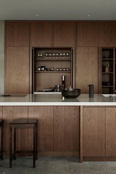 a large kitchen with wooden cabinets and white counter tops, along with bar stools