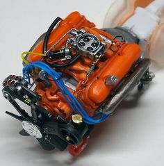 an orange car engine with wires attached to it's front end on a white surface