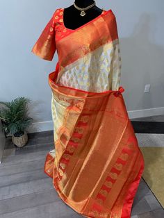 Right in time for Durga Puja, this grand and gorgeous Banarasi semi silk saree pours its richness elegantly through the zari and stone work. The saree is off white shade with golden zari bhuttis and intricate zari work on the pallu and border. Also seen embedded in the saree, are small stones that makes this saree a perfect wear for evening occasions or under the light occasions. Border, blouse and pallu are red shade. Falls and pico are done on the saree. Blouse is fully stitched. Size of the b Mirror Work Lehenga Choli, Banarasi Sari, Mirror Work Lehenga, Silk Saree Banarasi, Work Lehenga, Beautiful Mirror, Durga Puja, Zari Work, Under The Lights