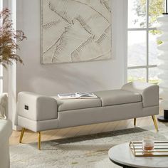 a living room with a white couch and coffee table in front of a painting on the wall