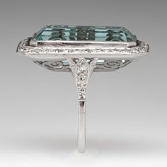 This mazing vintage cocktail ring is centered with one (1), bezel set, emerald cut natural aquamarine that is bordered with thirty-six (36), bead set, round single cut diamonds. The shoulders of the ring are each accented with three (3), bead set, round single cut diamonds. The gemstones are bordered with milgrain edging. The ring measures 28.9mm X 18.7mm at the top, rises 9.1mm above the finger, tapering to 1.7mm wide and 1.3mm thick at the base of the shank. It is currently a size 7. Art Deco Diamond Topaz Ring, Luxury White Gold Octagon Topaz Ring, Formal Rectangular Emerald Ring With Center Stone, Elegant Aquamarine Baguette Cut Jewelry, Octagonal Emerald Ring With Diamond Accents For Formal Events, Elegant Baguette Cut Aquamarine Jewelry, Octagon Emerald Ring With Diamond Accents For Formal Events, Luxury Octagon Emerald Ring With Accent Stones, Rectangular Platinum Jewelry With 17 Jewels