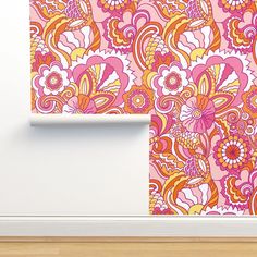 an orange and pink floral wallpaper on a white wall next to a wooden floor