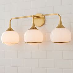 three light bathroom fixture on white brick wall