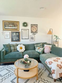 a living room with green couches and pictures on the wall above it, along with a coffee table