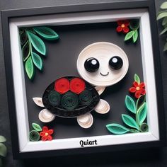 an origami tortoise with red flowers and leaves on the side in a black frame