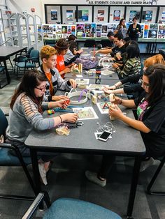 a group of people sitting around a table playing a game with nintendo wii motes