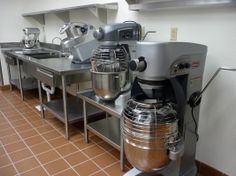 an industrial kitchen with stainless steel appliances and brown tile flooring on the walls,