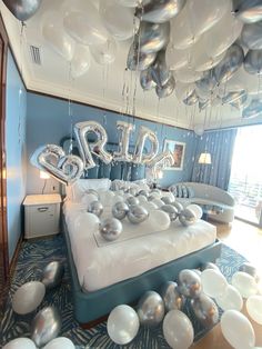 balloons are floating in the air above a bed that is surrounded by silver and white balls