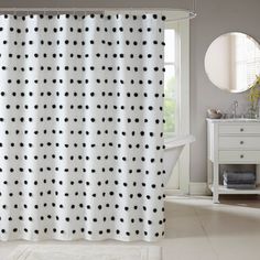 a white and black polka dot shower curtain in a bathroom with a mirror on the wall