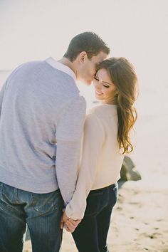 a man and woman standing next to each other on the beach