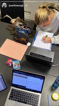 two laptops are sitting on a table with notebooks and pens in front of them