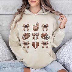 🌟"We" aim to steal the hearts of football fans with our comfortable and stylish design for stylish football fans. 🏈👕 Coquette Football Hoodie, Game Day Couture Hoodie, Football Bow Hoodie, Fall Football Lover Hoodie, Gift Autumn Hoodie For Football Mom  Welcome to TrendswayStore! You are where you can find your style and comfort. We are here to introduce you to the latest trends and quality products. Start exploring now We wish you pleasant shopping! PRODUCT DETAILS -Fit: Relaxed fit, suitable for both men and women (unisex). -Material: Made from 50% cotton and 50% polyester. -Ribbing: 1 x 1 rib with spandex, likely on the cuffs and waistband for better stretch and recovery.- -Hood: Double-lined hood for extra warmth and durability. -Drawcord: Color-matched drawcord for adjusting the ho Sports Fan Hoodie With Long Sleeves, Sports Fan Long Sleeve Hoodie, Team-colored Hoodie For Game Day In Fall, Team Spirit Long Sleeve Hoodie For Game Day, Game Day Sports Fan Long Sleeve Hoodie, Game Day Team Spirit Long Sleeve Hoodie, Winter Long Sleeve Sports Fan Hoodie, Sports Fan Long Sleeve Hoodie For Fall, Sports Fan Long Sleeve Hoodie For Winter