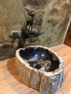 a sink made out of a tree stump on a wooden table next to a faucet