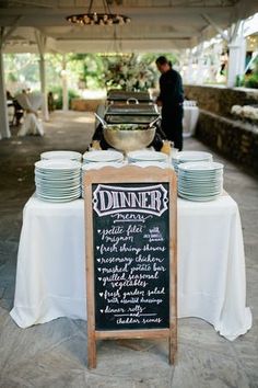 a table set up with plates and menus for an outdoor wedding reception at the park