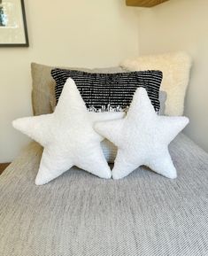 two white star pillows sitting on top of a bed