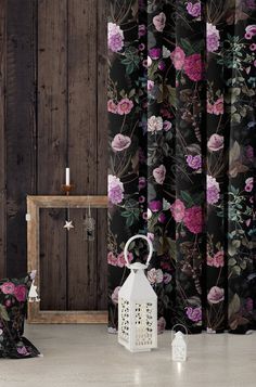 a white lantern sitting on top of a floor next to a wall covered in flowers