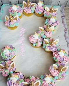 cupcakes are arranged in the shape of a heart with unicorn's on them