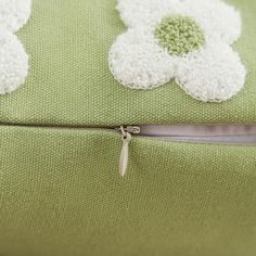 a green and white pillow with crocheted flower appliqued on it