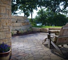 a wooden bench sitting on top of a stone patio next to a tree and water