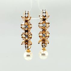 Gorgeous freshwater pearl dangly earrings plated with gold plating in excellent condition. Studded with champagne cubic zirconia, these will light up a room once you walk in.  Size :  50x11 mm Material : Metal Alloy, Faux Pearl, Champagne Crystal Plating : Gold See other items from my store here https://www.etsy.com/shop/GalantaJewels?ref=hdr_shop_menu Packaging : All products purchased from us come in a gift box. If you need to include a message, kindly leave us a note when purchasing.  Care Re Elegant Gold Jeweled Danglers, Gold Jeweled Pearl Earrings, Gold Flower Earrings With Pearl Drop For Party, Gold Pearl Drop Flower Earrings For Party, Gold-plated Jeweled Bridal Earrings, Gold Jeweled Pearl Earrings For Party, Formal Gold Pearl Drop Danglers, Gold Pearl Crystal Earrings For Party, Dangly Pearl Earrings