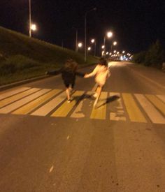 two people holding hands crossing the street at night