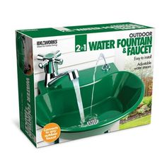 a green water fountain and faucet in a box