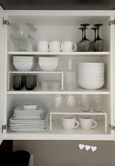 white dishes and cups are arranged on shelves in the kitchen, with hearts drawn on them