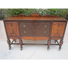 an old wooden dresser with ornate carvings on the front and sides, sitting in front of a wall