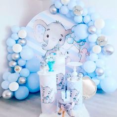 an elephant themed baby shower with blue and silver balloons on the wall behind it, along with other items