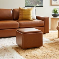 a brown leather couch and ottoman in a living room with a rug on the floor