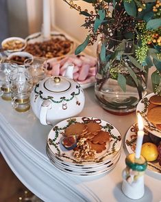 a table topped with plates and cups filled with food next to a vase full of flowers