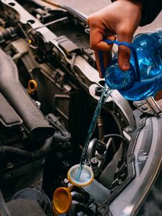 a person pouring water into a car engine